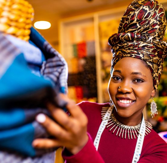 tanzanian woman with snake print turban over hear working in fabrics shop .